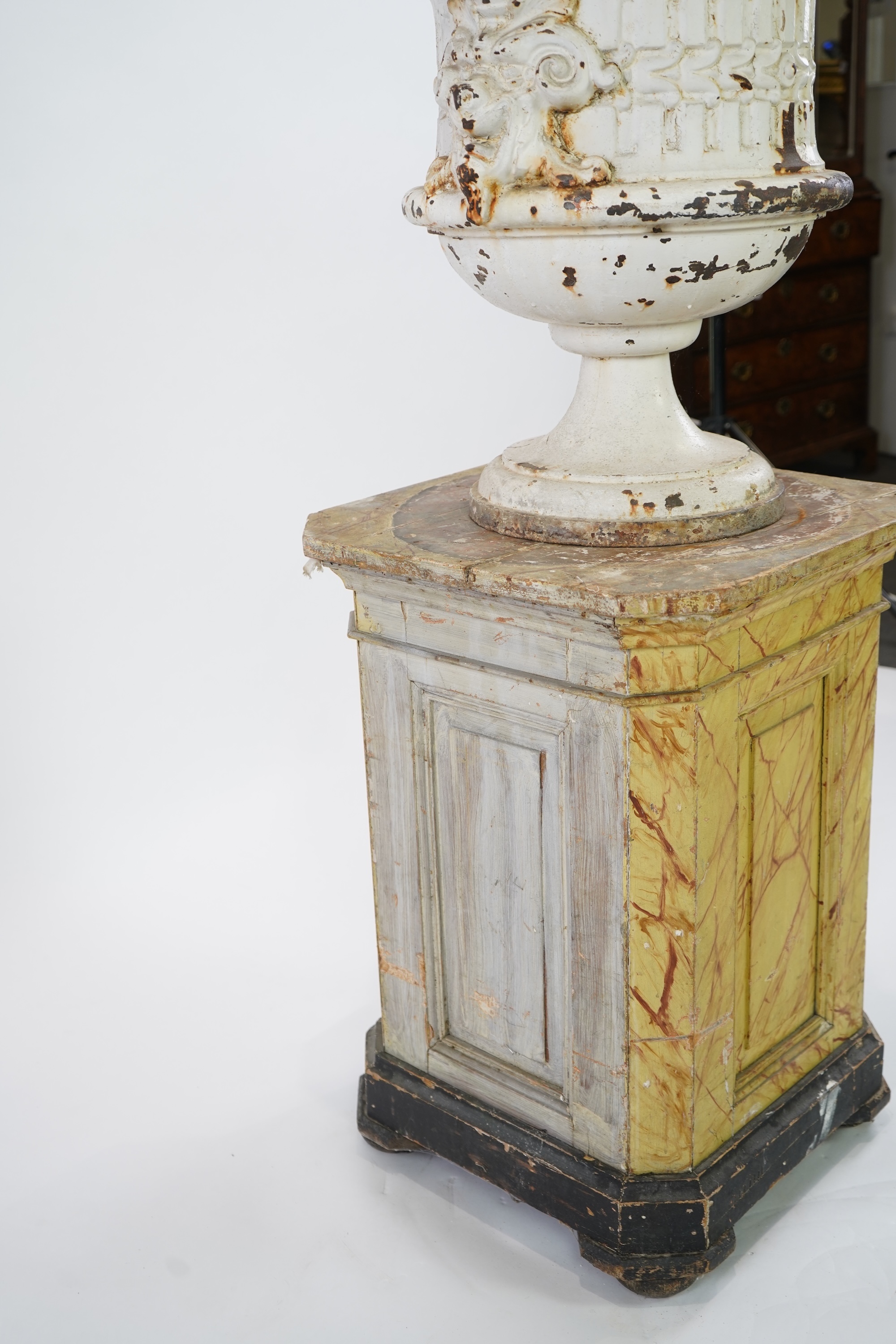 A Victorian white painted cast iron urn and a painted faux marble pedestal
